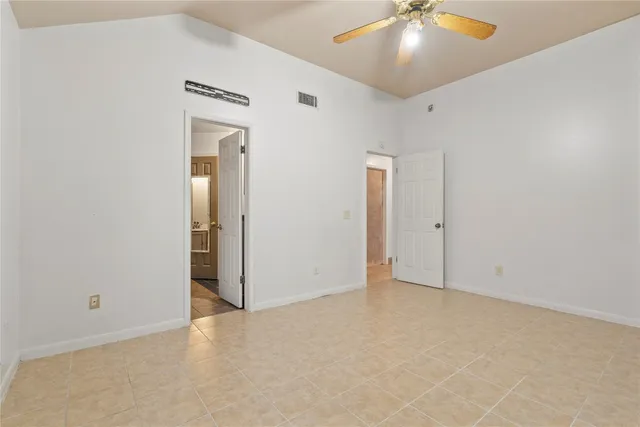 an empty room with a ceiling fan and closet area
