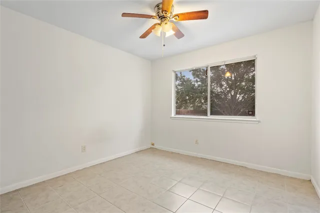an empty room with chandelier fan and windows