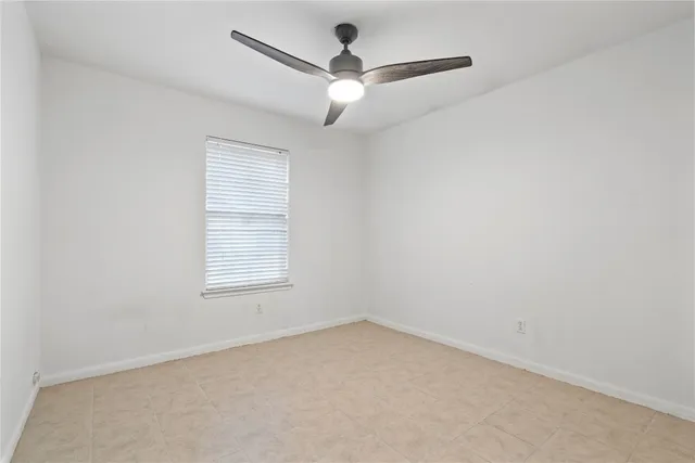 an empty room with a window and a ceiling fan
