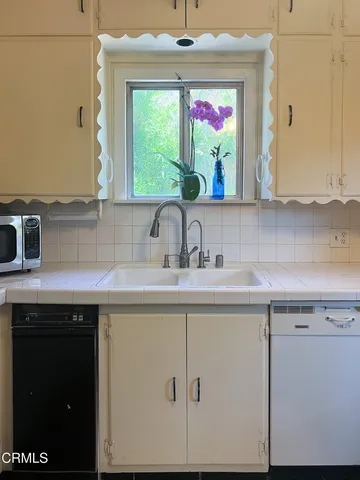 a view of a dining room and kitchen with a table chairs a workspace and a window