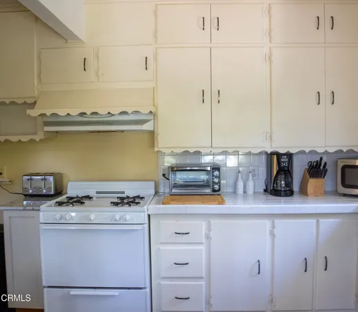 a kitchen with a sink a stove a refrigerator and white cabinets