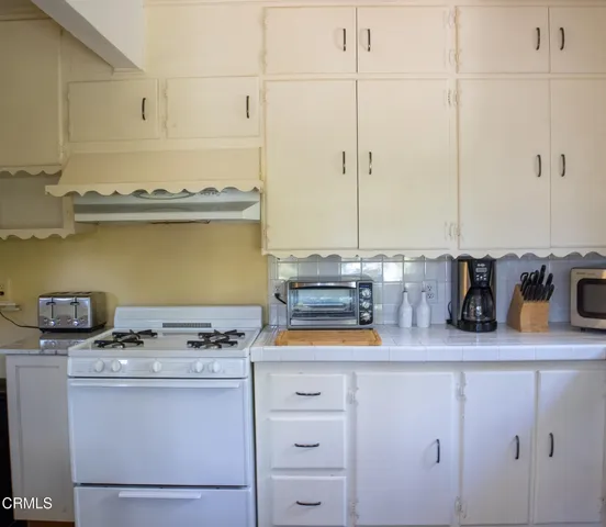 a kitchen with a sink a stove a refrigerator and white cabinets