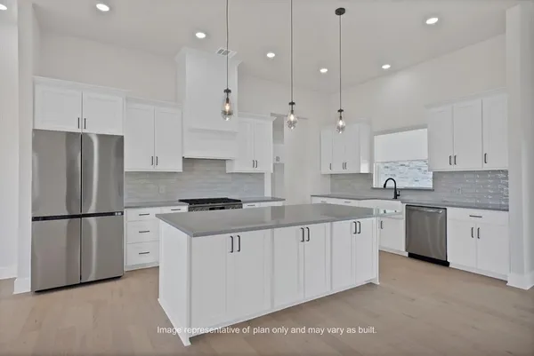 a kitchen with granite countertop a refrigerator a sink and white cabinets