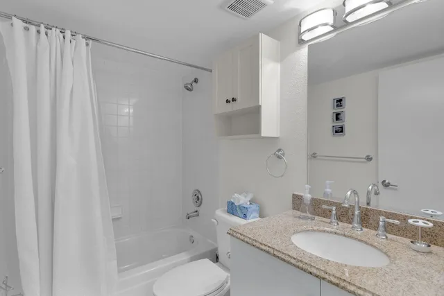 a bathroom with a granite countertop sink a toilet and shower