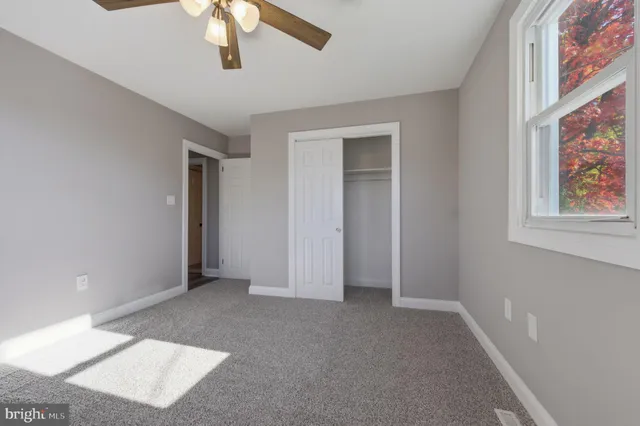 an empty room with a window and a fan