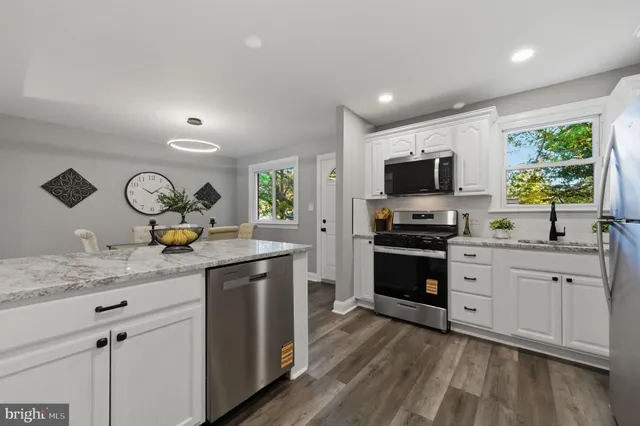 a kitchen with granite countertop a sink appliances cabinets and a counter top space