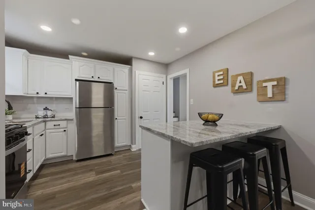 a kitchen with stainless steel appliances granite countertop a refrigerator a stove a sink a refrigerator white cabinets and wooden floor