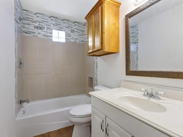 a bathroom with a granite countertop sink toilet and mirror