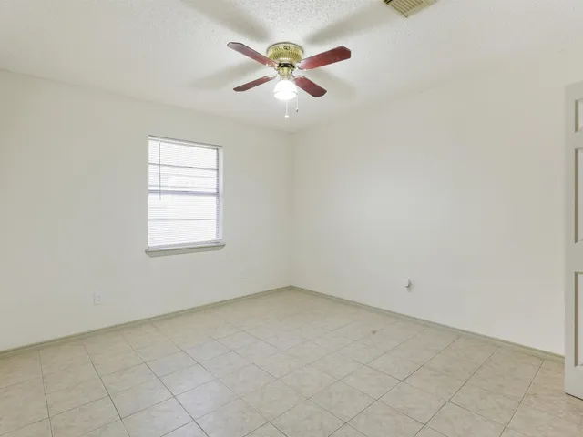 an empty room with ceiling fan and window