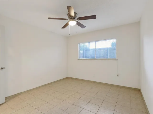 an empty room with a ceiling fan and windows