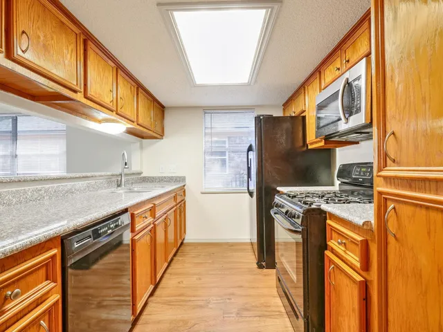a kitchen with stainless steel appliances granite countertop a refrigerator a stove and a sink