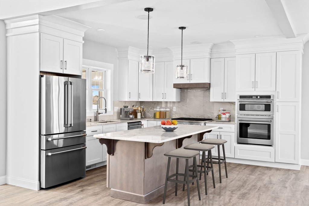 a kitchen with stainless steel appliances granite countertop a refrigerator a stove a sink and a refrigerator with white cabinets