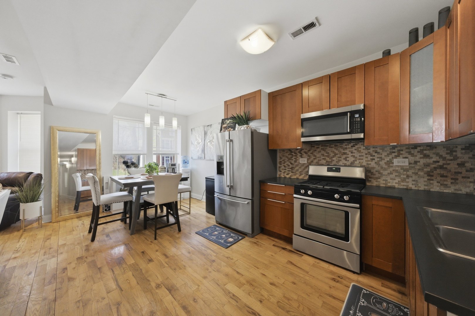 1253 South Tripp Avenue Chicago, IL 60623 - Photo 11 of 21 a kitchen with stainless steel appliances granite countertop a stove top oven a sink dishwasher a dining table and chairs with wooden floor