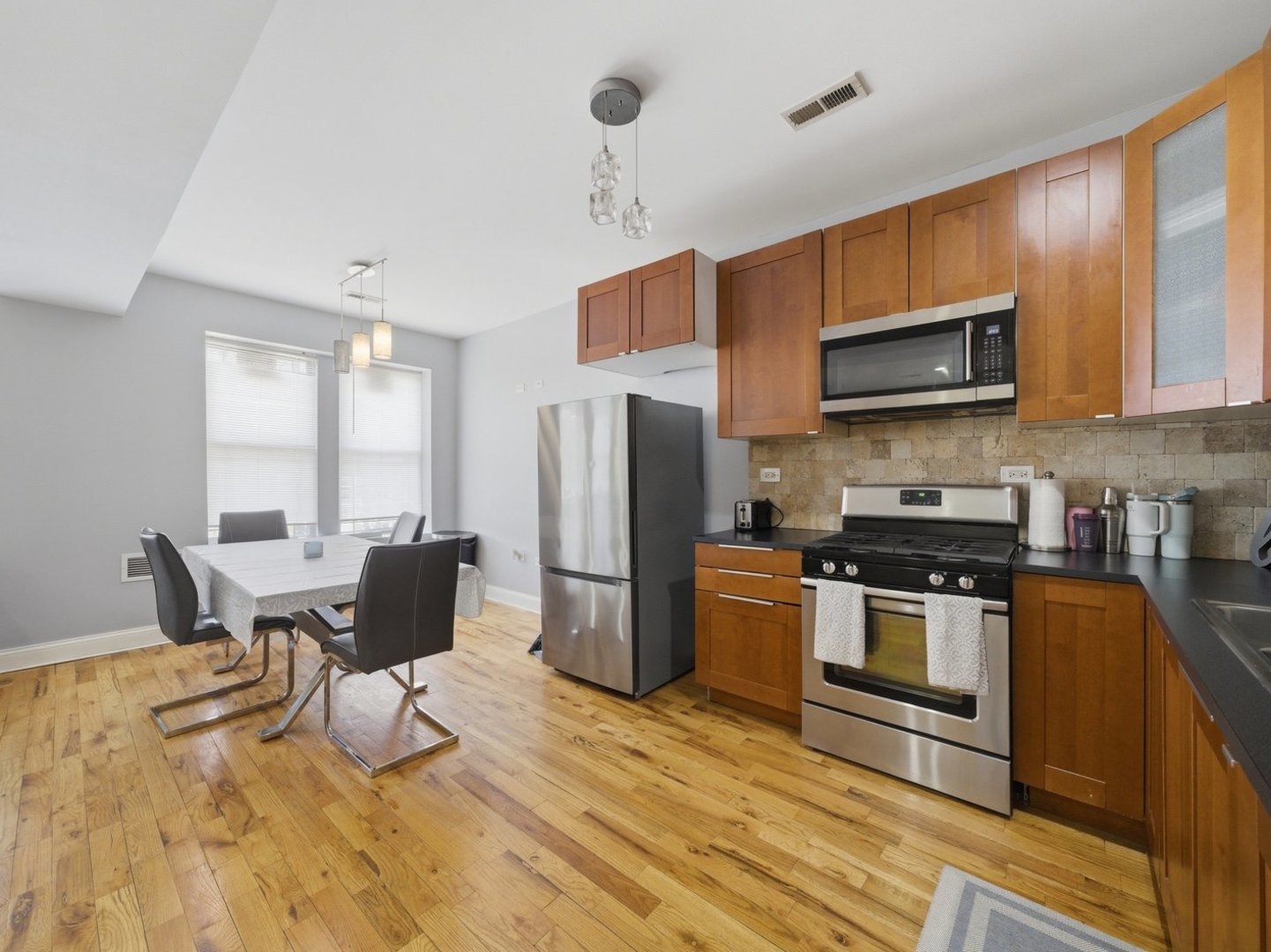 1253 South Tripp Avenue Chicago, IL 60623 - Photo 4 of 21 a kitchen with stainless steel appliances granite countertop a stove top oven a sink dishwasher a dining table and chairs with wooden floor