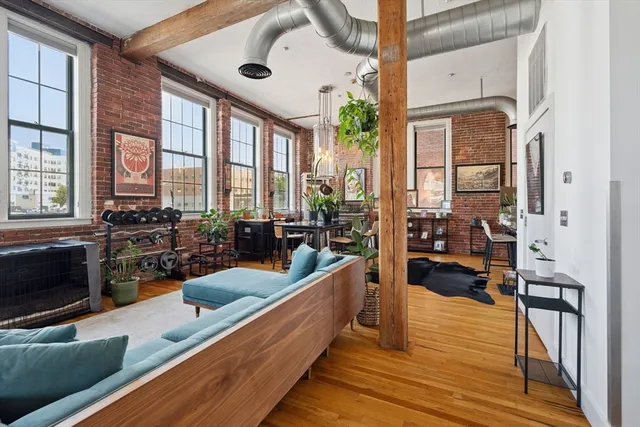 a large living room with stainless steel appliances kitchen island granite countertop a large window and a wooden floor