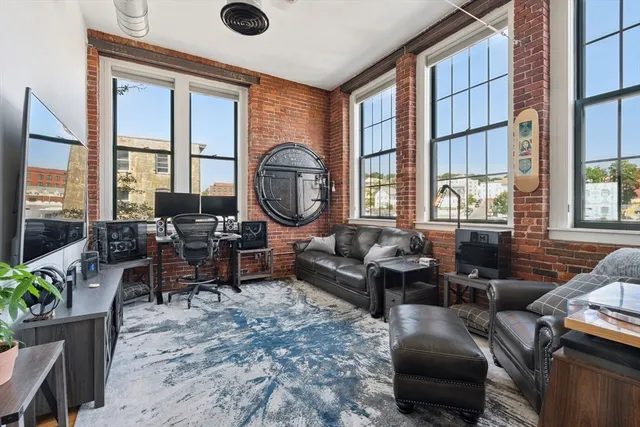 a living room with furniture a large window and wooden floor