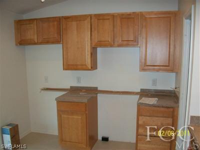 8136 Anhinga Road Fort Myers, FL 33967 - Photo 4 of 6 a room with a refrigerator and cabinets