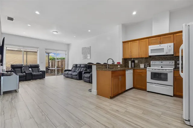 a kitchen with granite countertop kitchen island stainless steel appliances a sink stove and cabinets