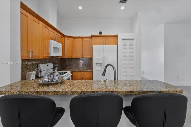 a view of a hallway with wooden floor and a refrigerator