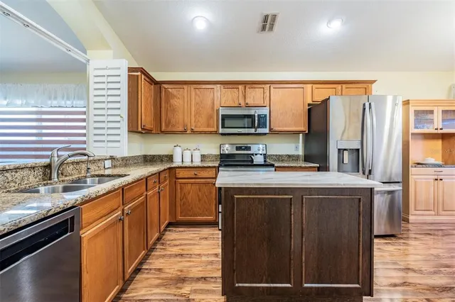 a kitchen with stainless steel appliances granite countertop a stove a sink dishwasher and a refrigerator