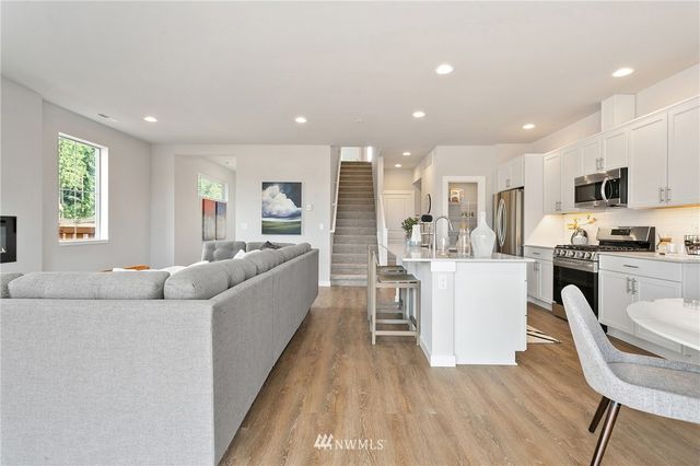 a kitchen with stainless steel appliances granite countertop a stove top oven a sink dishwasher and a refrigerator with wooden floor