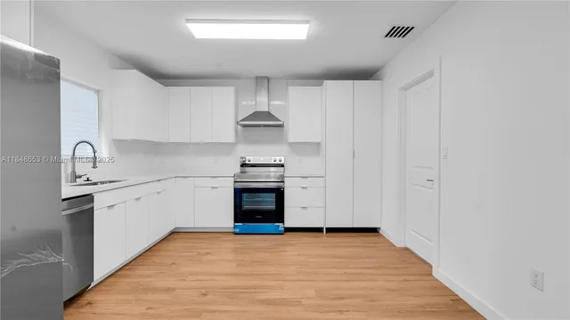 a kitchen with granite countertop a sink cabinets stainless steel appliances and a window