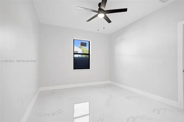 an empty room with a window and a ceiling fan