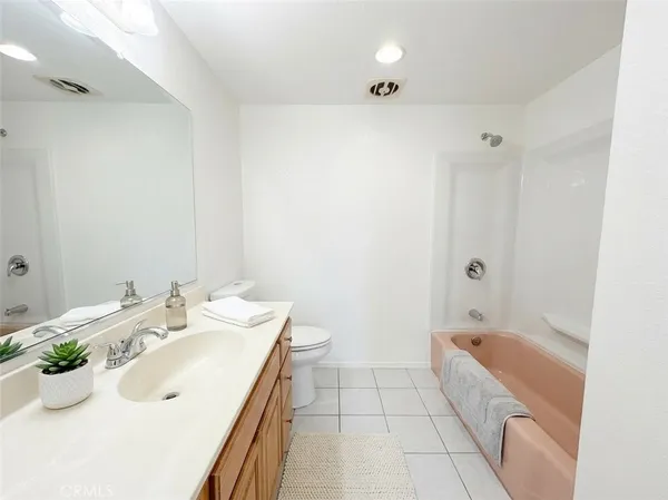 a bathroom with a tub sink vanity and mirror