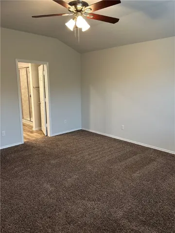 an empty room with a chandelier fan and windows