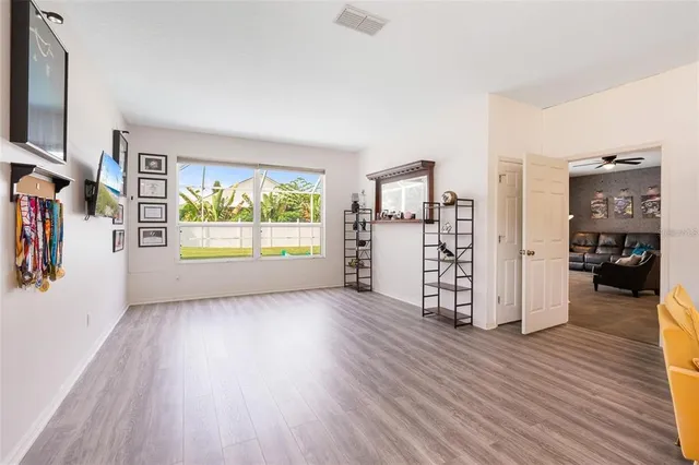 a view of an empty room with window and wooden floor