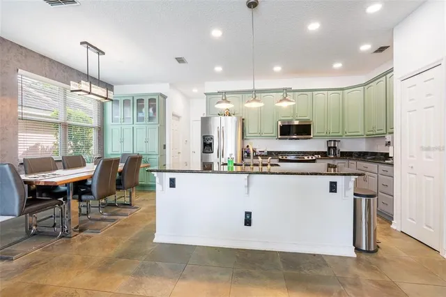 a large kitchen with kitchen island a sink a counter top space and stainless steel appliances