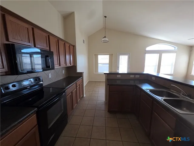 a kitchen with stainless steel appliances a sink a stove a refrigerator a sink and cabinets