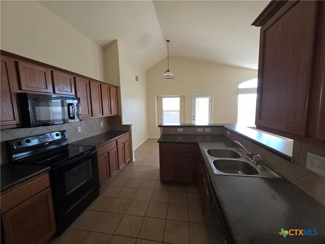 a kitchen with stainless steel appliances granite countertop a stove a sink and a microwave
