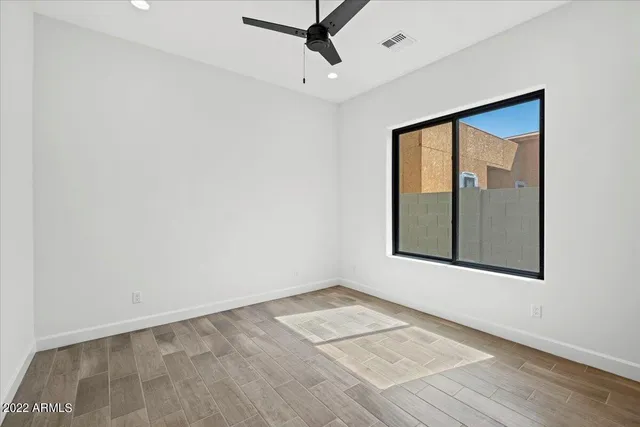 an empty room with wooden floor and windows