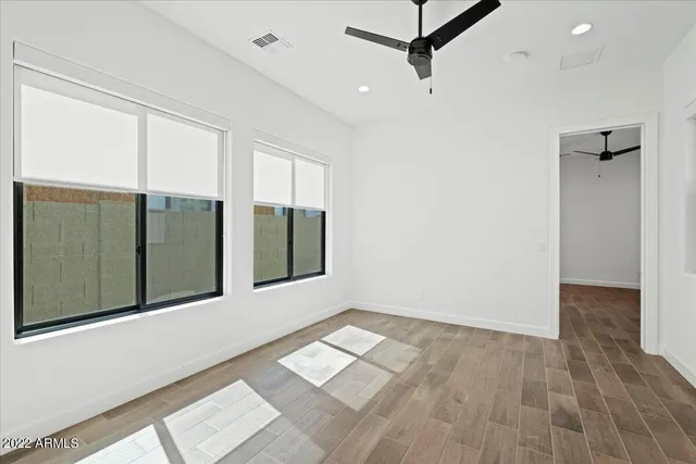 a view of an empty room with window and wooden floor