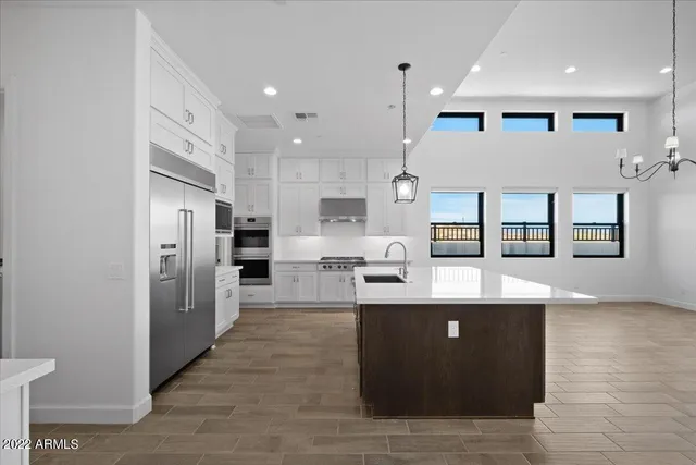 a large kitchen with stainless steel appliances kitchen island granite countertop a refrigerator and a sink