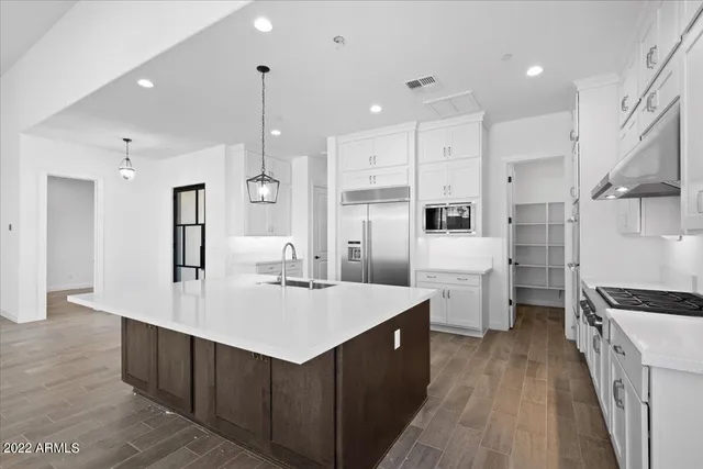 a kitchen with stainless steel appliances kitchen island granite countertop a refrigerator a sink dishwasher and a stove with wooden floor