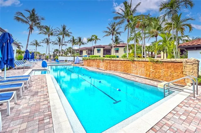 a view of swimming pool with a yard and palm trees