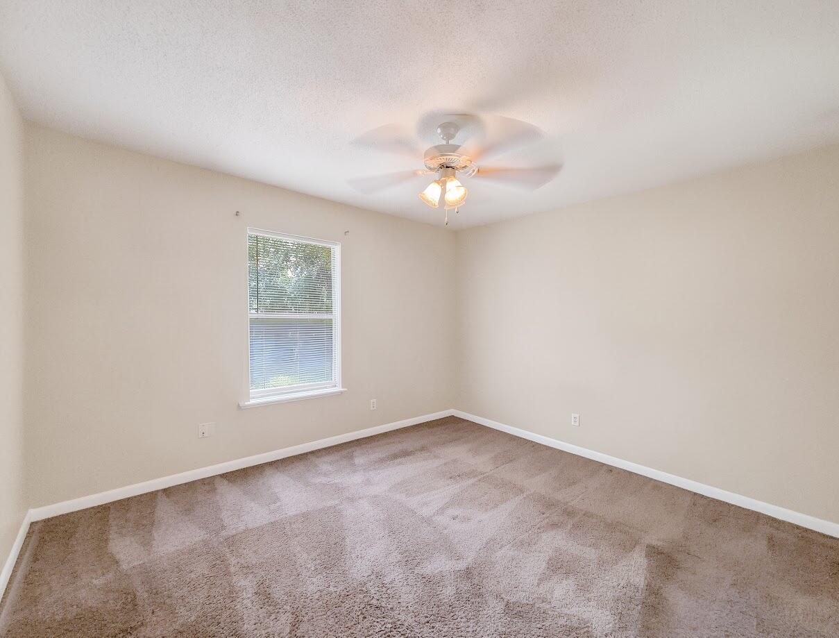 208 Squirrel Haven Road, Unit A Mary Esther, FL 32569 - Photo 10 of 16 an empty room with a chandelier fan and windows