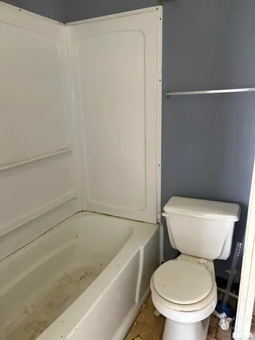 a white toilet sitting next to a bath tub