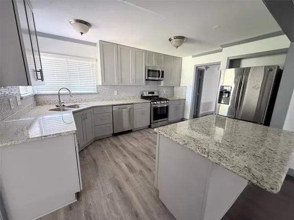 a kitchen with stainless steel appliances granite countertop a sink stove refrigerator and wooden cabinets