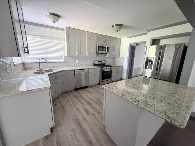 a kitchen with stainless steel appliances granite countertop a sink stove refrigerator and wooden cabinets