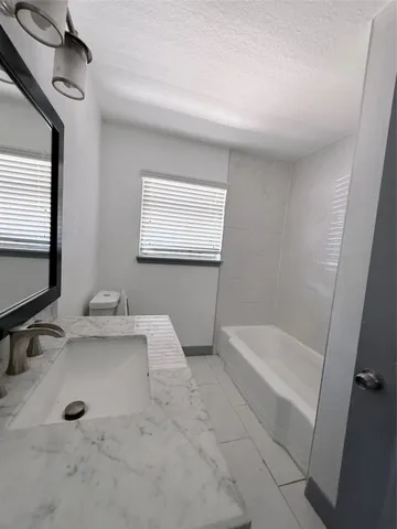 a bathroom with a tub a sink and mirror