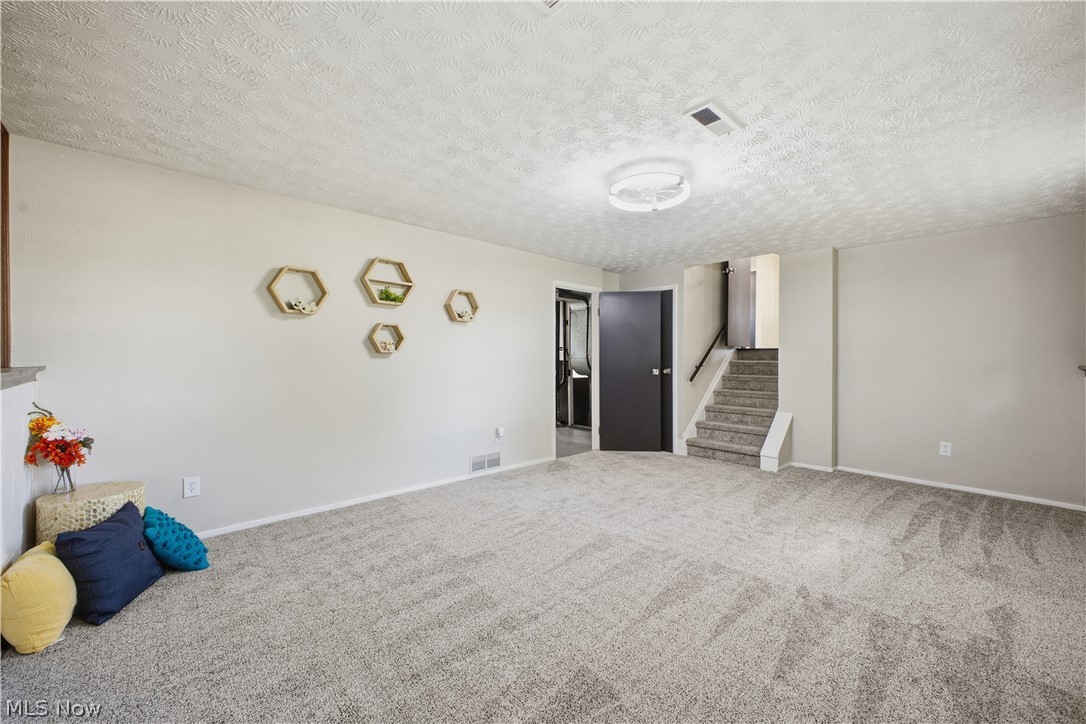 4845 New Road Austintown, OH 44515 - Photo 19 of 40 Carpeted flooring throughout, neutral wall paint, ceiling-mounted light fixture, and interior staircase with railing