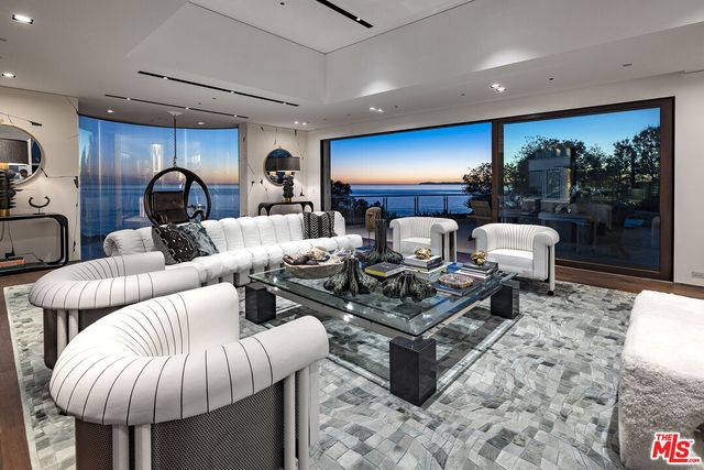 a living room with a black white checkered floor with couches chair and a stove