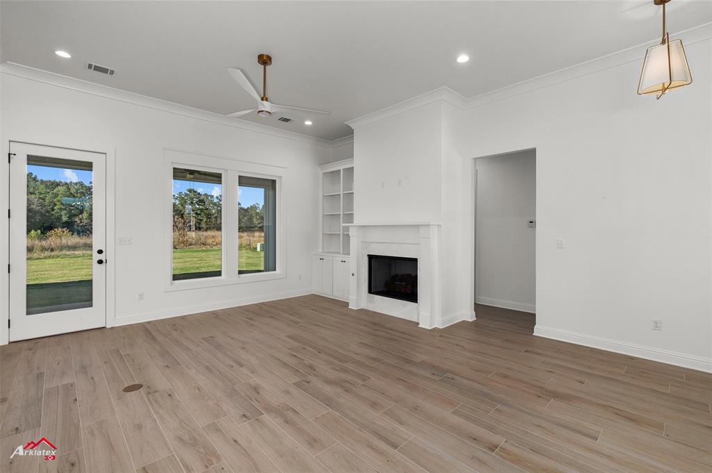 35 Turtle Creek Drive Benton, LA 71006 - Photo 9 of 32 an empty room with wooden floor a ceiling fan a fireplace and windows