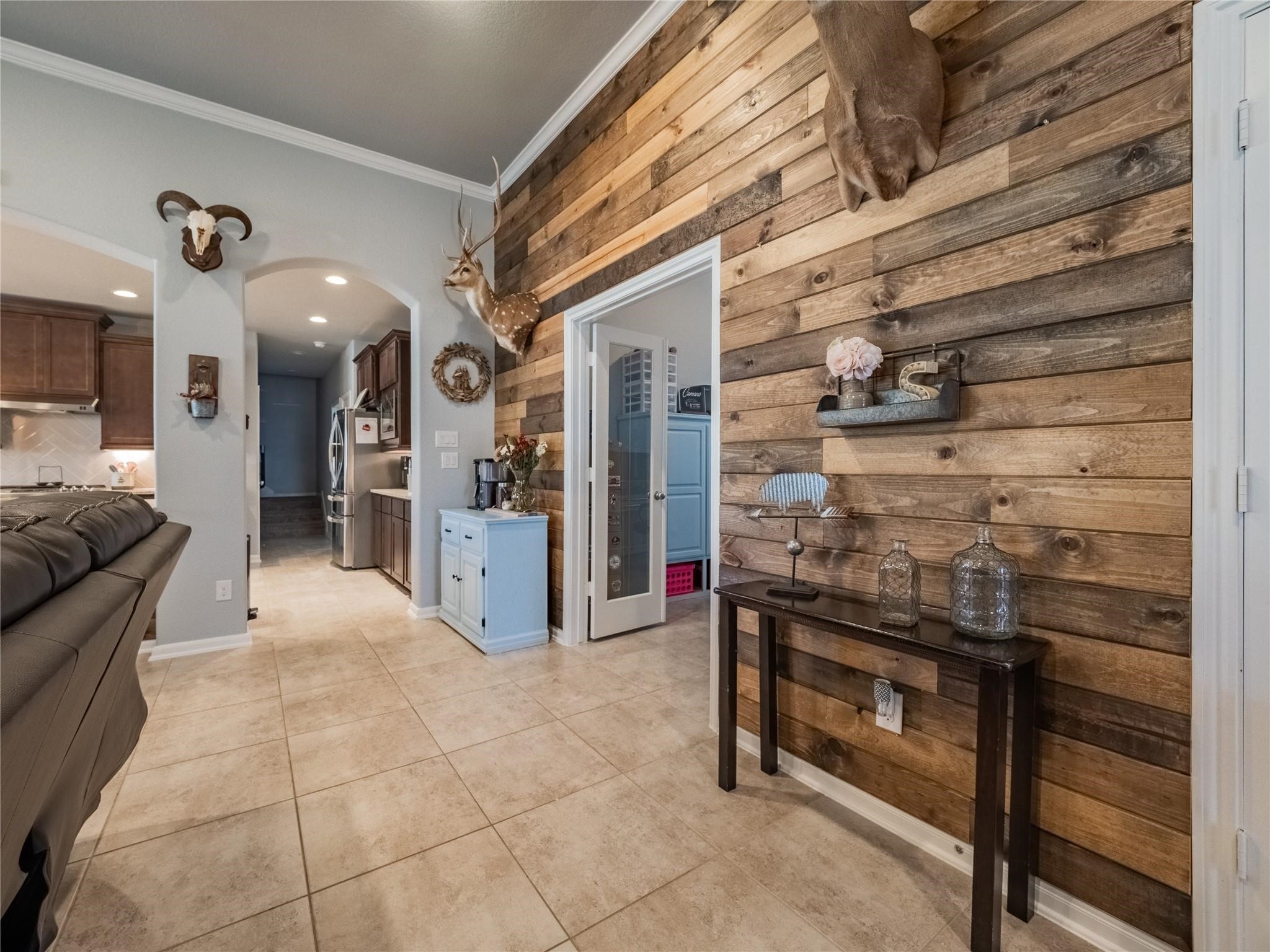 10215 Lewis Lane Iowa Colony, TX 77583 - Photo 12 of 45 Entryway view showcasing a wood accent wall for added character. Glass French doors provide access to the office on the left. The home features upgraded crown molding, and the office includes a built-in double desk.