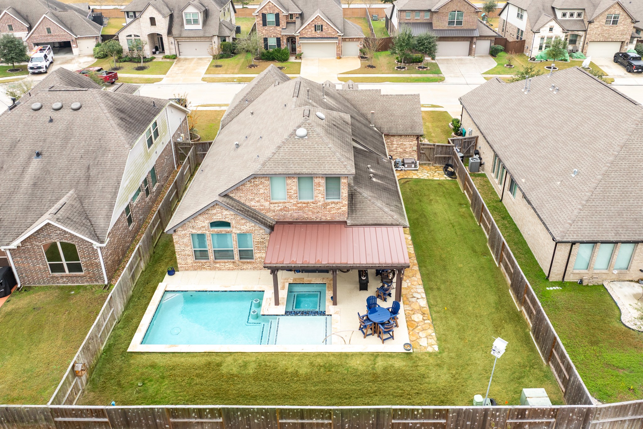 10215 Lewis Lane Iowa Colony, TX 77583 - Photo 3 of 45 Aerial view of backyard featuring a 5-foot pool, an eight-person hot tub, an oversized tanning ledge, a covered patio, and a stone accent border.