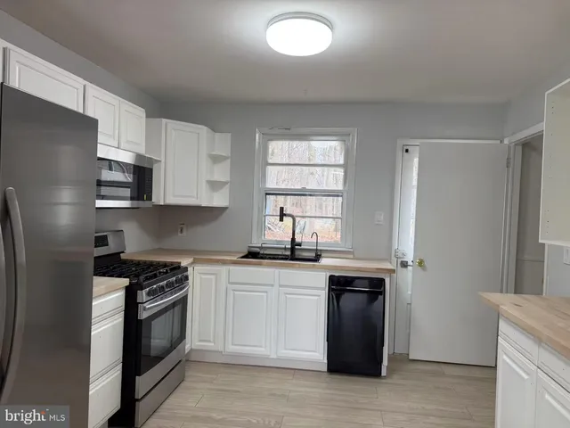 a kitchen with stainless steel appliances granite countertop white cabinets a sink a stove a refrigerator and a microwave