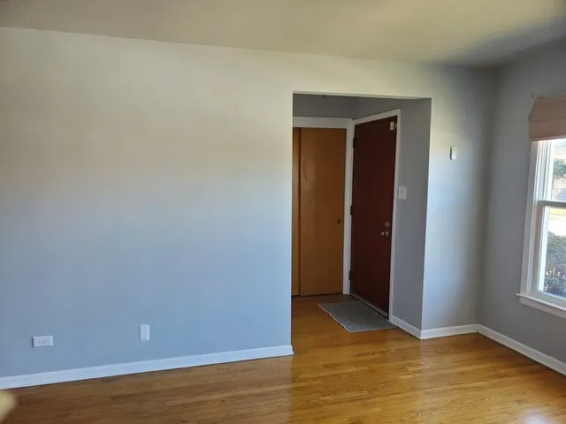 a view of an empty room with window and wooden floor